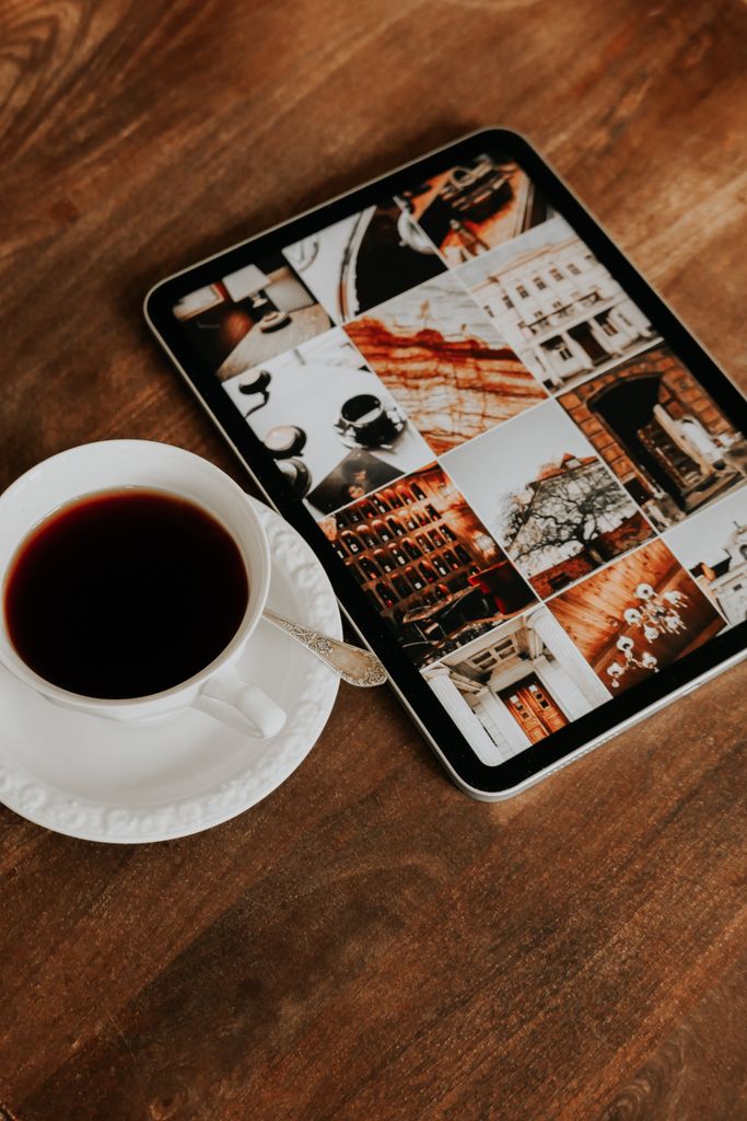 Warm coffee beside a tablet displaying urban and architectural photography.